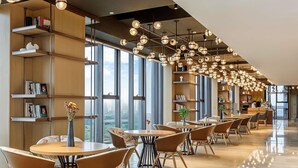 A modern cafe with round tables and chairs, large windows, and hanging spherical lights. - Swissotel Hot Spring Hotel Xi'an Xinxing (Xi'an)