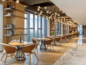 A modern cafe with round tables and chairs, large windows, and hanging spherical lights. - Swissotel Hot Spring Hotel Xi'an Xinxing (Xi'an)