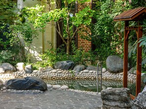A stone pathway leading to a small pond with a wooden structure on the right. - Swissotel Hot Spring Hotel Xi'an Xinxing (Xi'an)