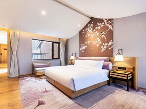 A modern hotel room with a large bed, a view of the city through the window, a decorative wall mural, and a bedside table with a lamp. - Swissotel Hot Spring Hotel Xi'an Xinxing (Xi'an)
