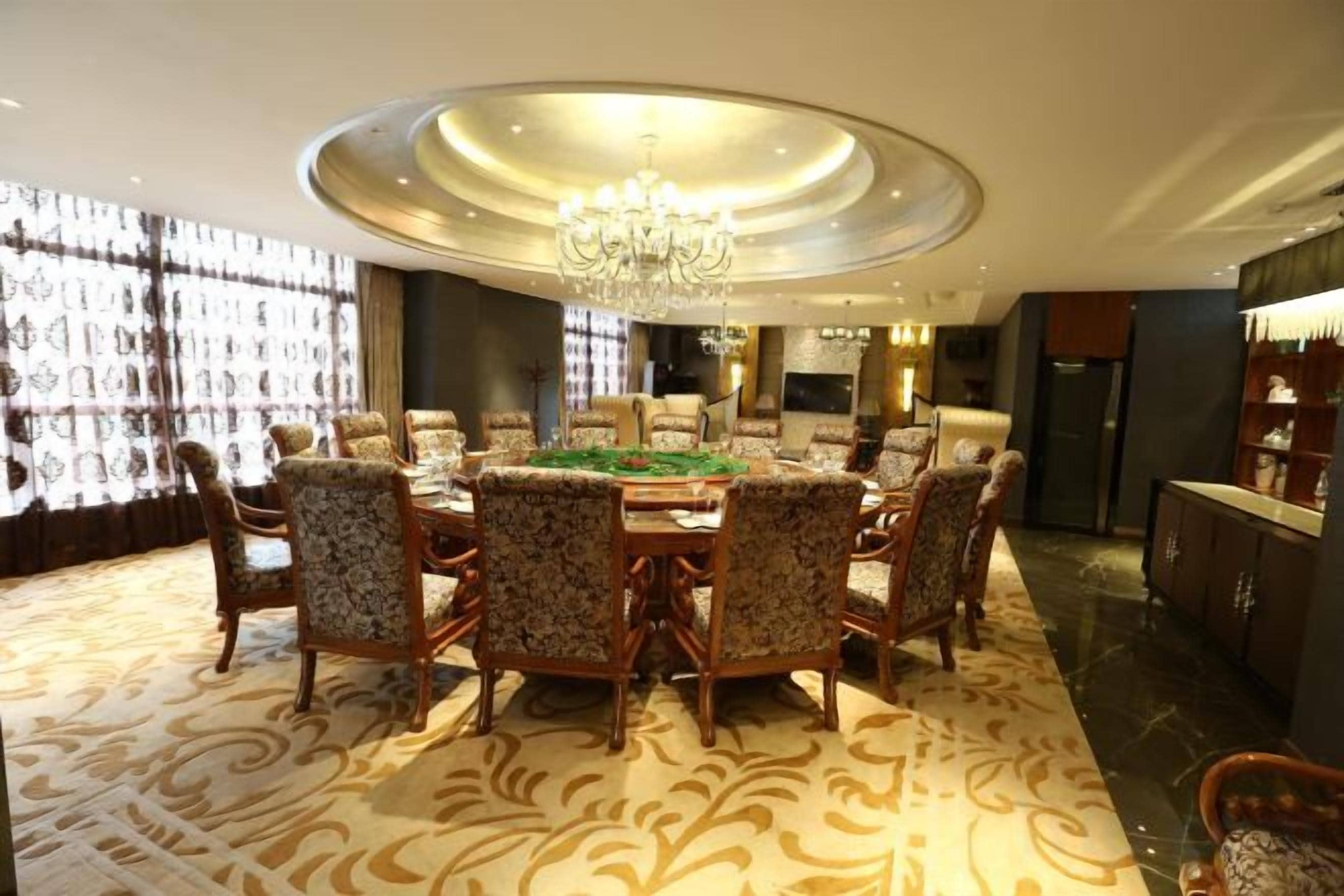 A dining area with a round table, chairs, and a chandelier.