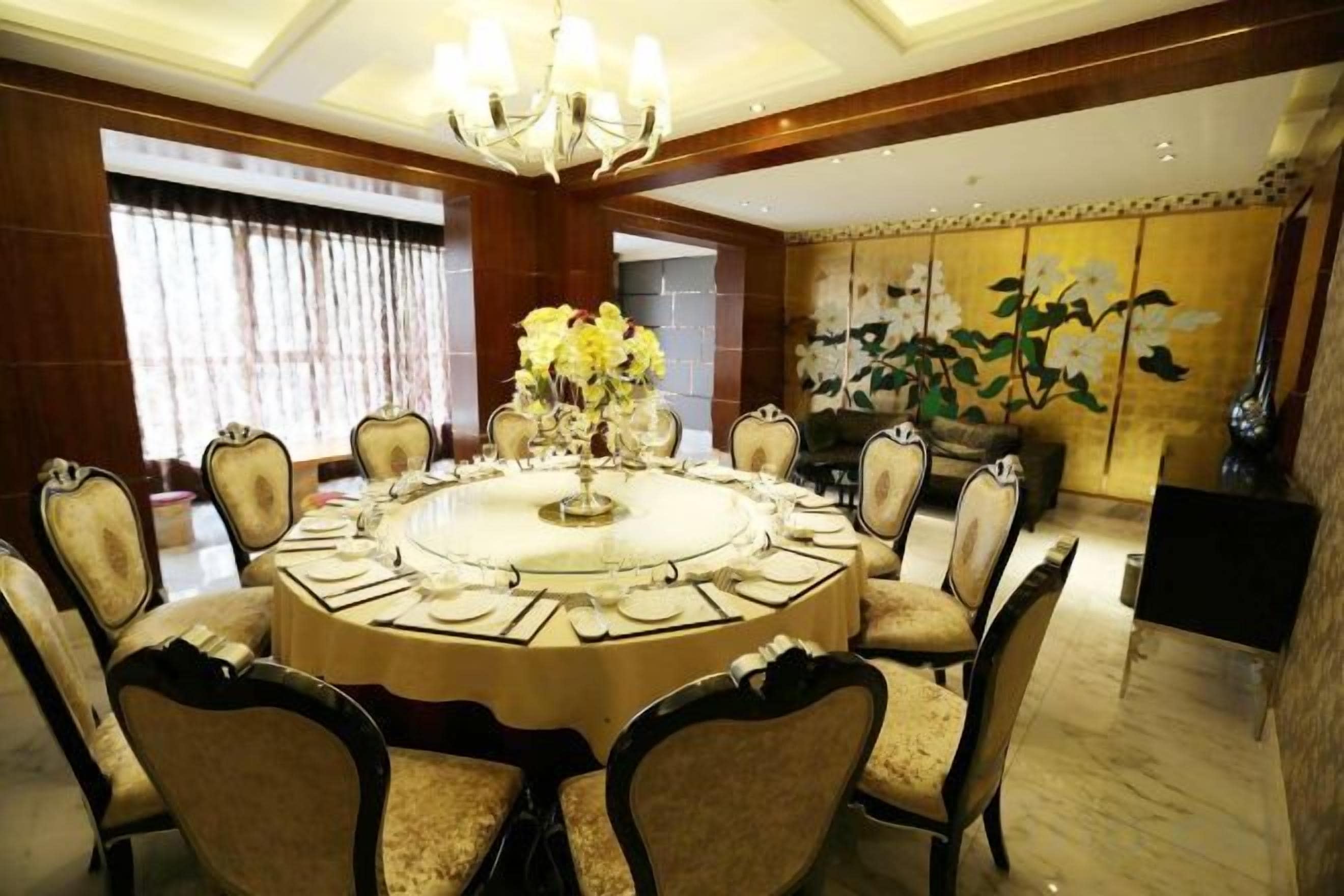 A round dining table with eight chairs, a chandelier, and a floral centerpiece.