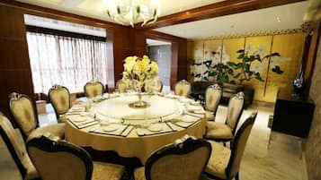 A round dining table with eight chairs, a chandelier, and a floral centerpiece.