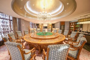 A round table with chairs, a chandelier, and a bar area. - Blossoming Quality Hotel (Xining)