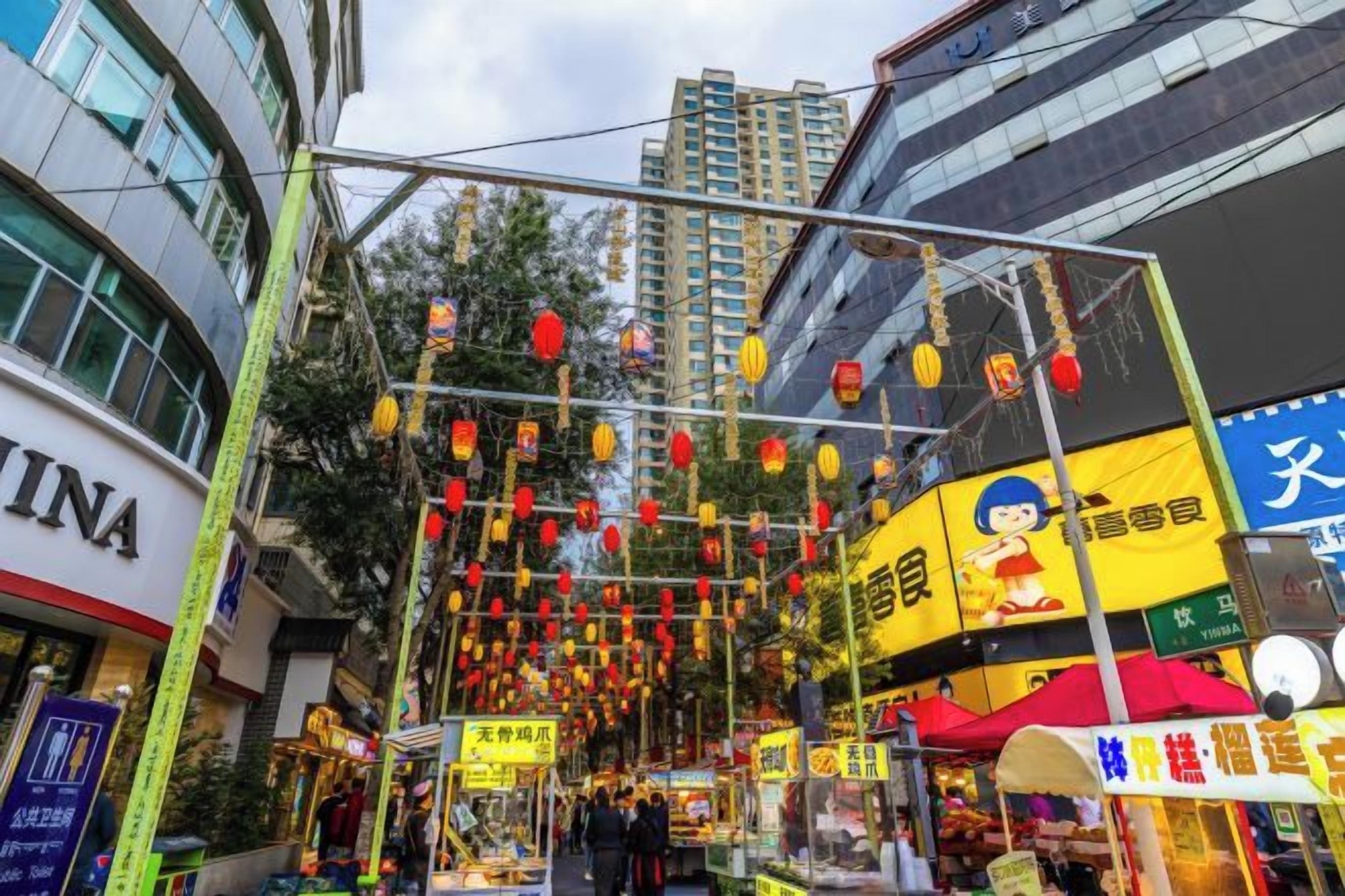 A street with a traditional Chinese lantern display, storefronts, and a building with signage.