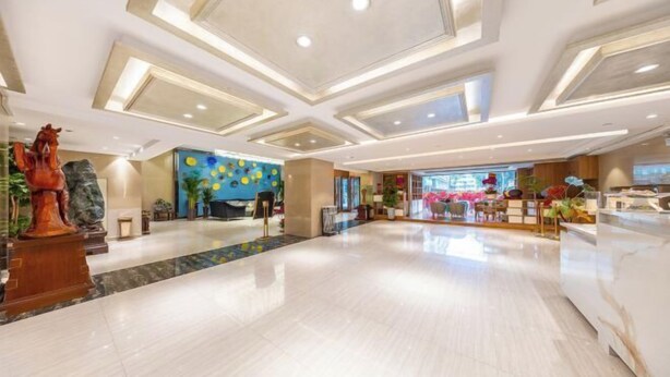 A spacious lobby with a marble floor, a reception desk, and a colorful mural on the wall.