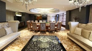 A spacious living room with a large round table, two sofas, and a chandelier.