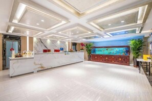 A hotel lobby with a marble reception desk, a large aquarium, and a modern ceiling design. - Blossoming Quality Hotel (Xining)