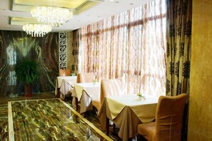 A dining area with tables set for four, a chandelier, and a patterned wall. - Blossoming Quality Hotel (Xining)