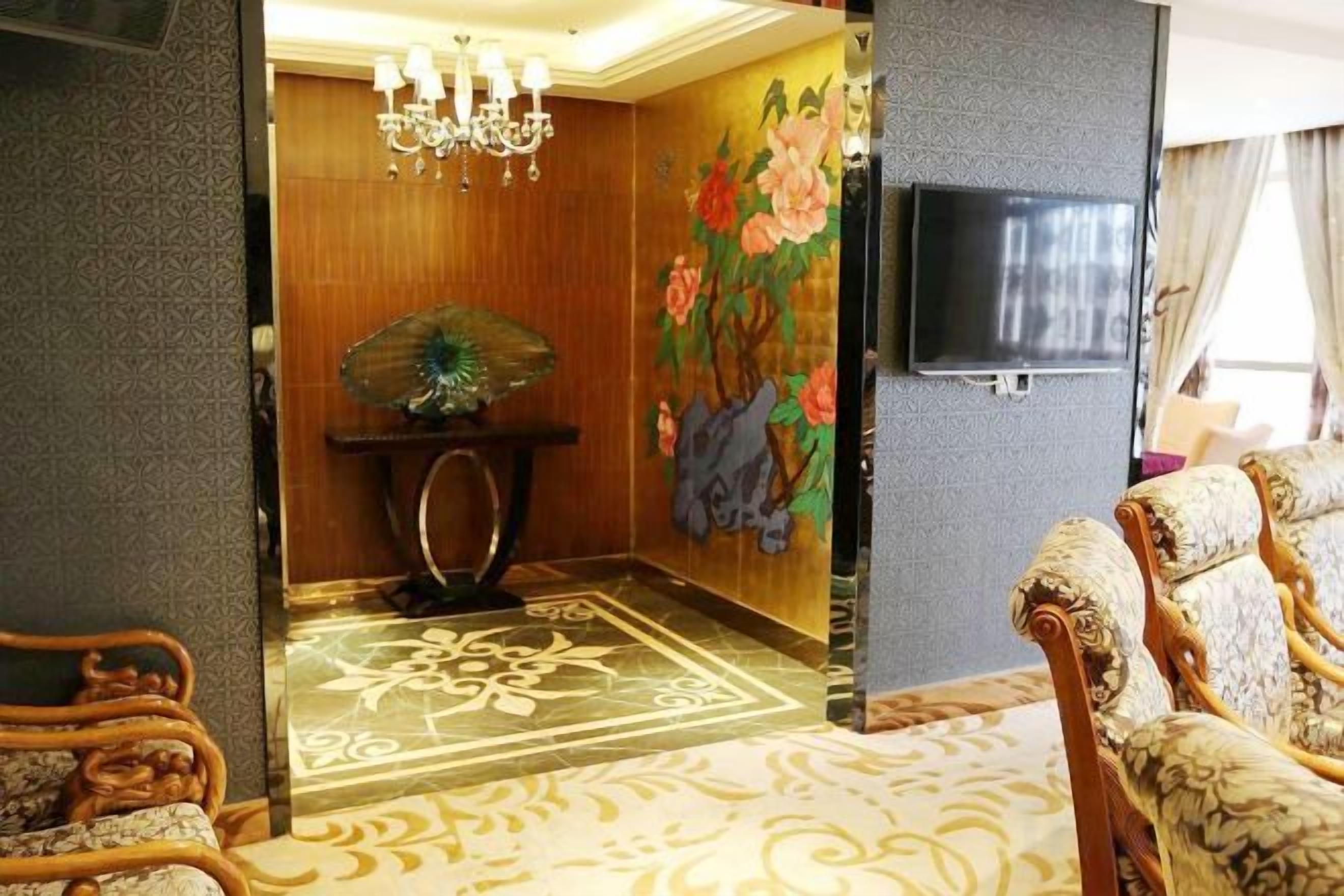 Una habitación con alfombra estampada, una consola de madera con un adorno, un televisor montado en la pared y sillones tapizados con detalles.