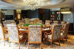 Comedor formal con una mesa redonda, sillas estampadas con motivos florales y un candelabro.