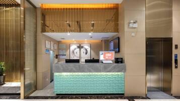 A reception area with a marble counter, a digital screen, and a reception desk.