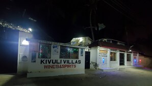 Un edificio con letreros que indican 'KIVULI VILLAS WINES&SPIRITS' y 'NYADZ BEAUTY AND FASHION SHOP'.