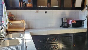 Una cocina con un lavaplatos doble, una cafetera y un microondas.