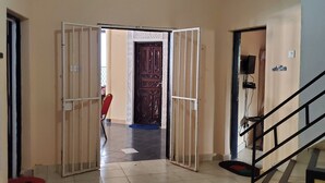 Un espacio interior amplio con suelo de baldosas, una escalera y una puerta que da a otra habitación.