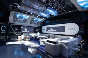 Una sala de control moderna con múltiples pantallas, un escritorio y asientos.