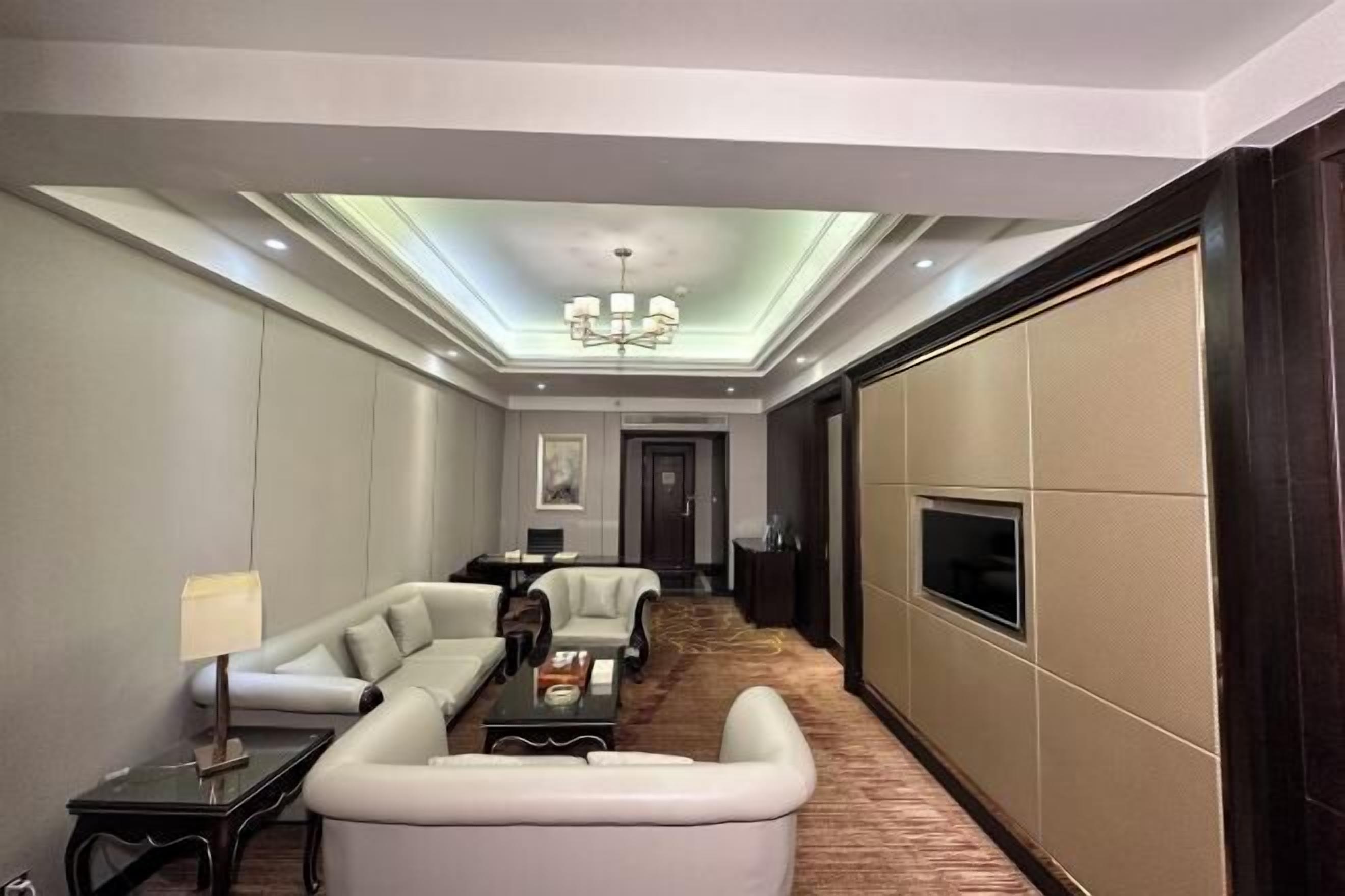 Una habitación de hotel moderna con un conjunto de sofás, una mesa de comedor y un televisor.