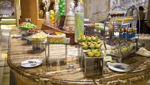 A buffet with various food items and desserts, including a cake and fruit cups, arranged on a marble counter. - Jiahua Hotel (Puning)