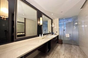 A modern bathroom with a large mirror, two sinks, and a glass shower enclosure. - Jiahua Hotel (Puning)
