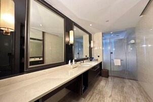 Un baño moderno con un espejo grande, dos lavamanos y una cabina de ducha de vidrio.