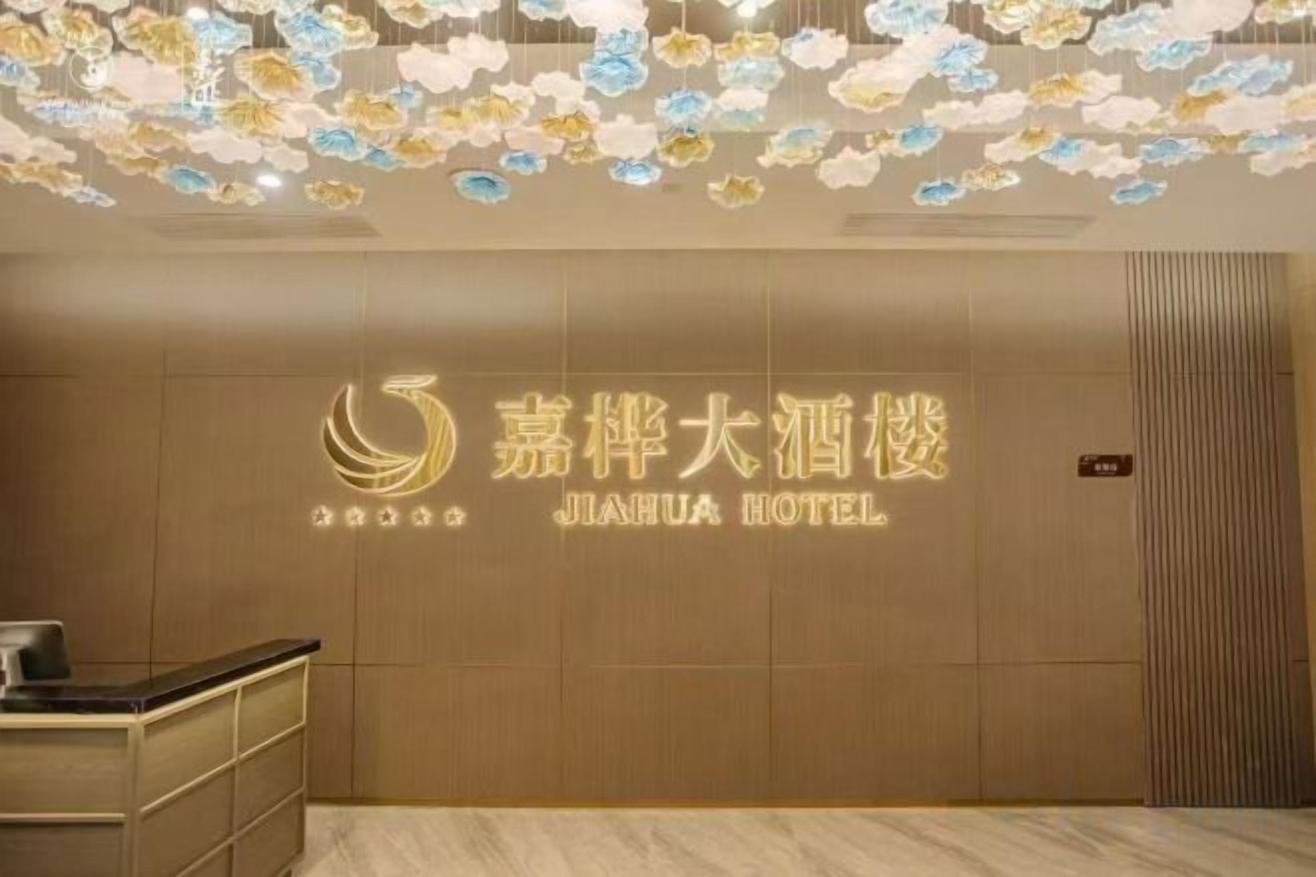 Ein Empfangsbereich mit einer Wandtafel für das Jiahua Hotel, einem Empfangstresen und einer Decke mit floralen Verzierungen.