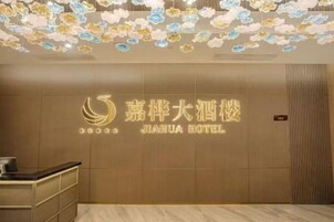 Zona de recepción con un cartel en la pared del Hotel Jiahua, un mostrador de recepción y un techo con decoraciones florales.