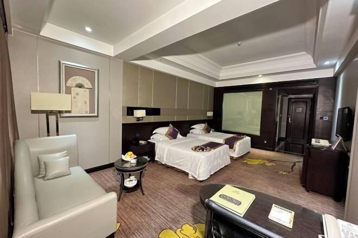 A hotel room with a bed, a sofa, a desk, a nightstand, and a mirror.