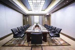 A conference room with a long table, chairs, and a chandelier. - Jiahua Hotel (Puning)