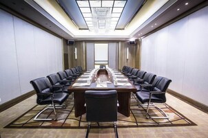 Un salón de conferencias con una larga mesa, sillas y una araña.