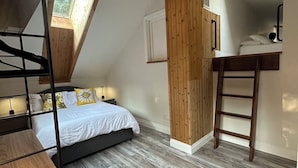 Ein Schlafzimmer mit einem Hochbett, einer Holzleiter, einem Schreibtisch und einem Deckenventilator.