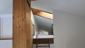 Ein Schlafzimmer im Loft-Stil mit einer Wand aus Holzlatten, einem Etagenbett und einer Leiter.