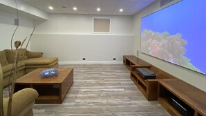Ein Heimkino mit großem Flachbildfernseher, Holzmöbeln und einem hellen Holzboden.