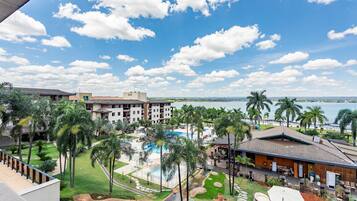 Un resort con piscina, palmeras y vista al océano.