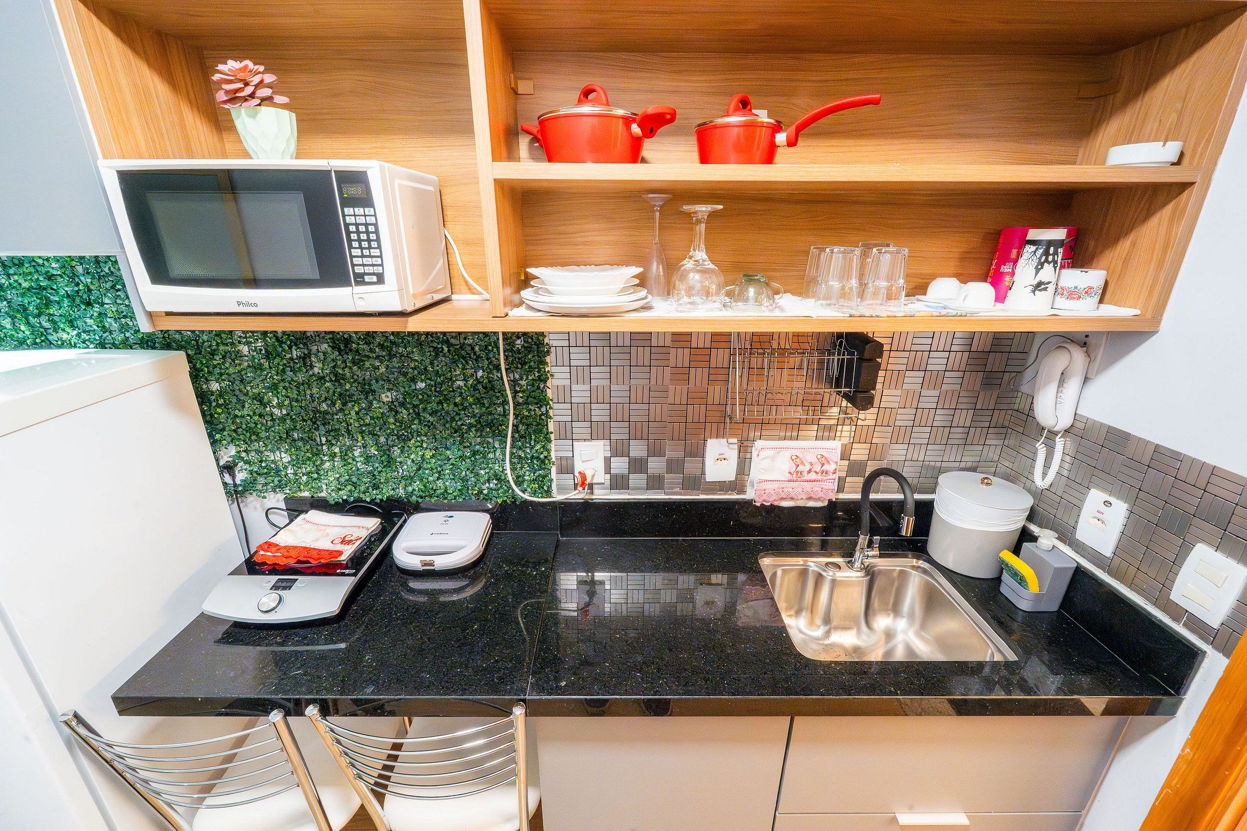 Una cocina compacta con microondas, lavamanos y una pequeña encimera.