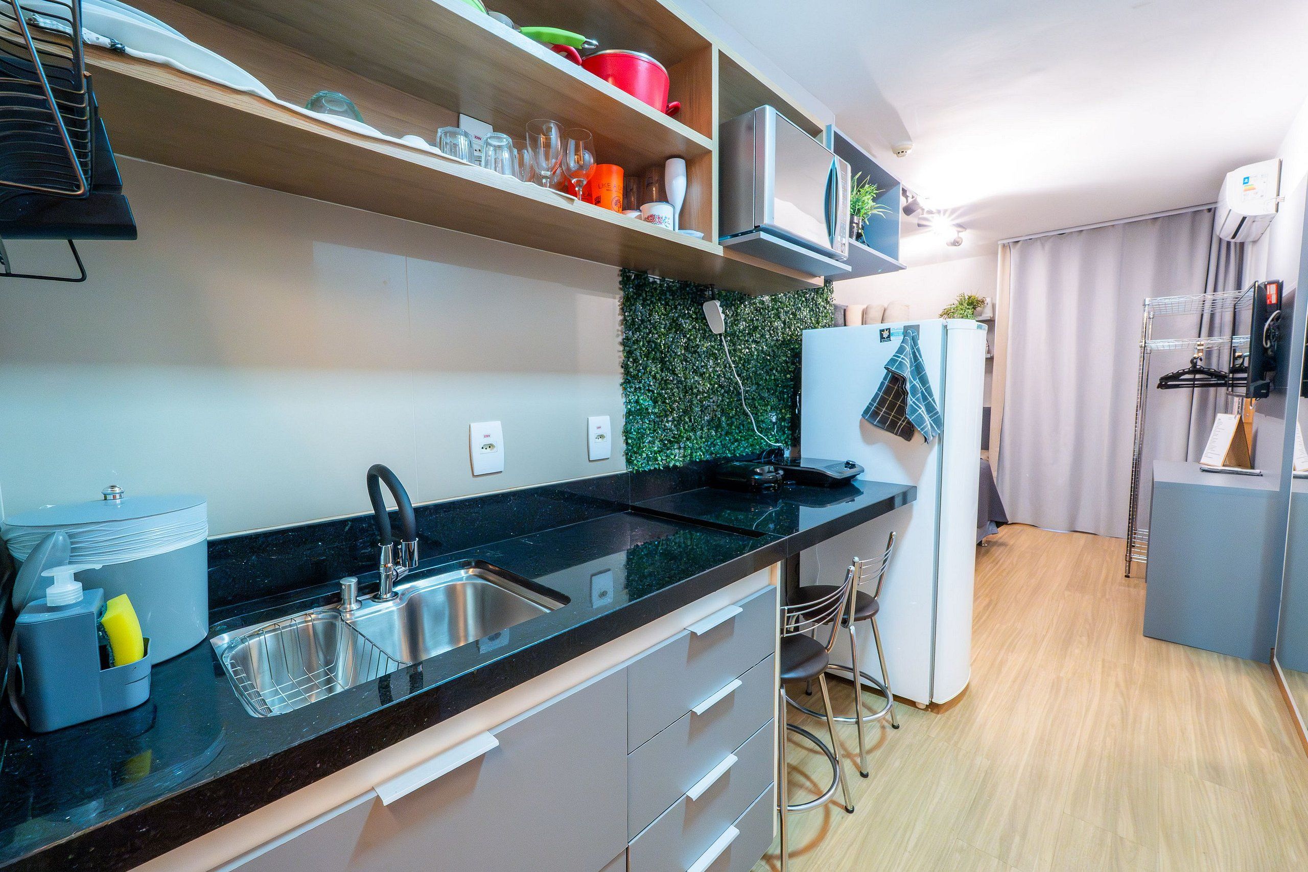 Una cocina moderna con encimera negra, pileta de acero inoxidable y alacenas blancas.