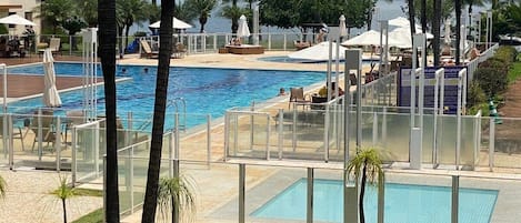 A pool area with multiple swimming pools, sun loungers, and umbrellas.