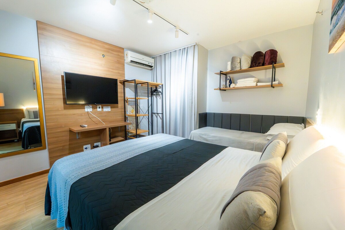 A modern hotel room with a large bed, a TV, a desk, and a wardrobe.