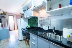 A modern kitchen with a black countertop, stainless steel sink, and white cabinets. - Life resort (Brasília)