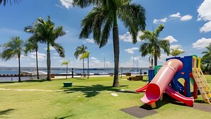 A playground with a slide and climbing structures, palm trees, and a view of the water. - Life resort (Brasília)