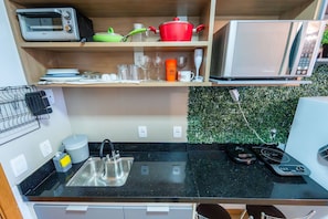 A kitchen with a microwave, toaster, sink, and a small countertop with a kettle and a coffee maker. - Life resort (Brasília)