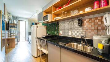 Uma cozinha moderna com bancada preta, pia de aço inoxidável e prateleiras de madeira.
