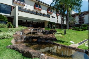 Un hotel con un giardino curato, che include una piccola cascata e grandi rocce.