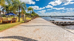 A paved walkway with benches, palm trees, and a view of the water. - Life resort (Brasília)