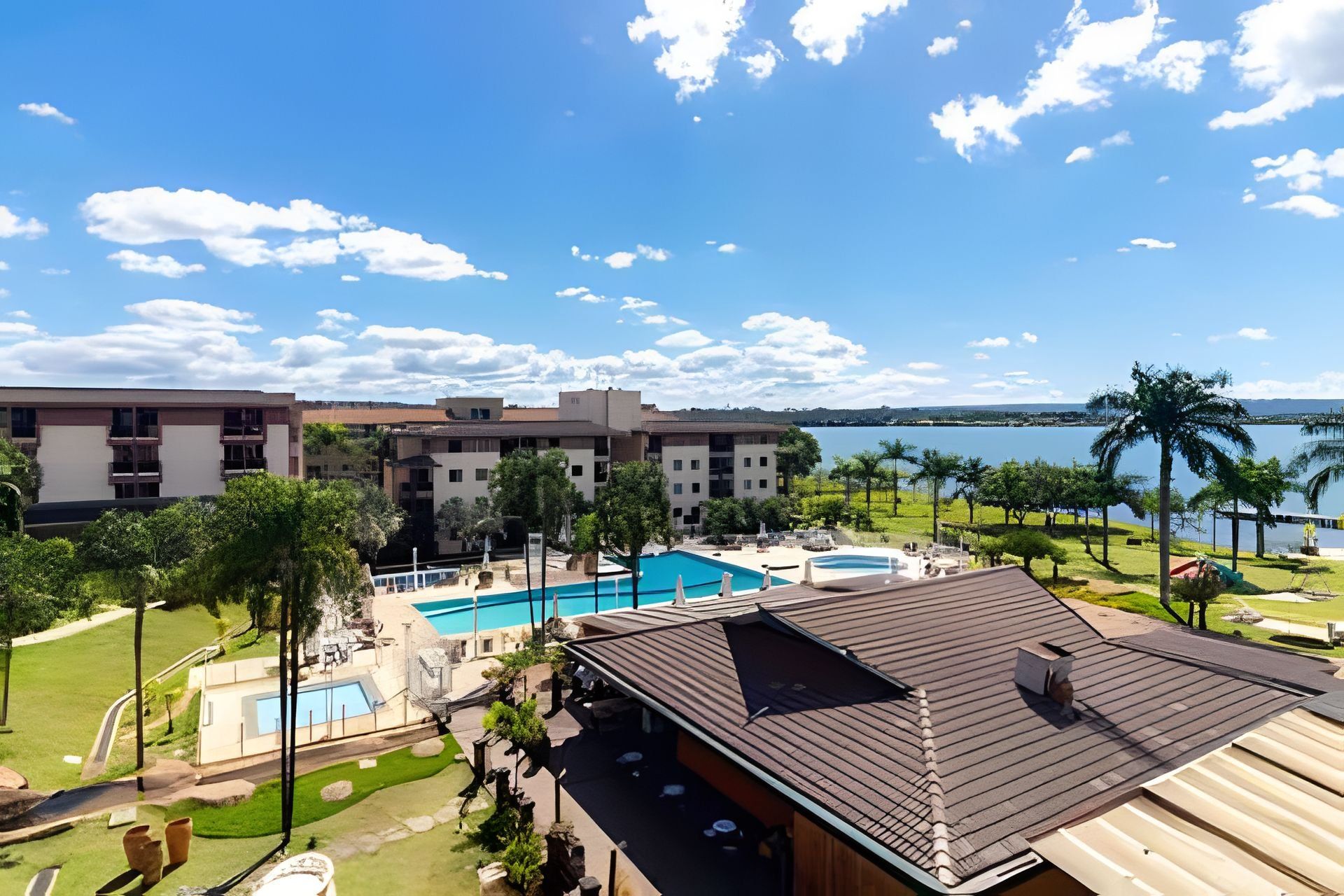 A resort with multiple swimming pools, a large building with balconies, and a view of a lake.