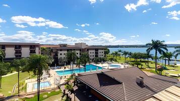 A resort with multiple swimming pools, a large building with balconies, and a view of a lake.