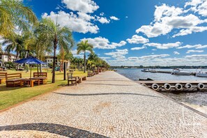 A paved walkway with benches, palm trees, and a view of the water. - Life resort (Brasília)