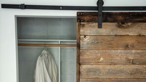 A room with a wooden sliding door, a white robe hanging on a rack, and a wicker basket on the floor. - The Manzanita Cottage (Sebastopol)