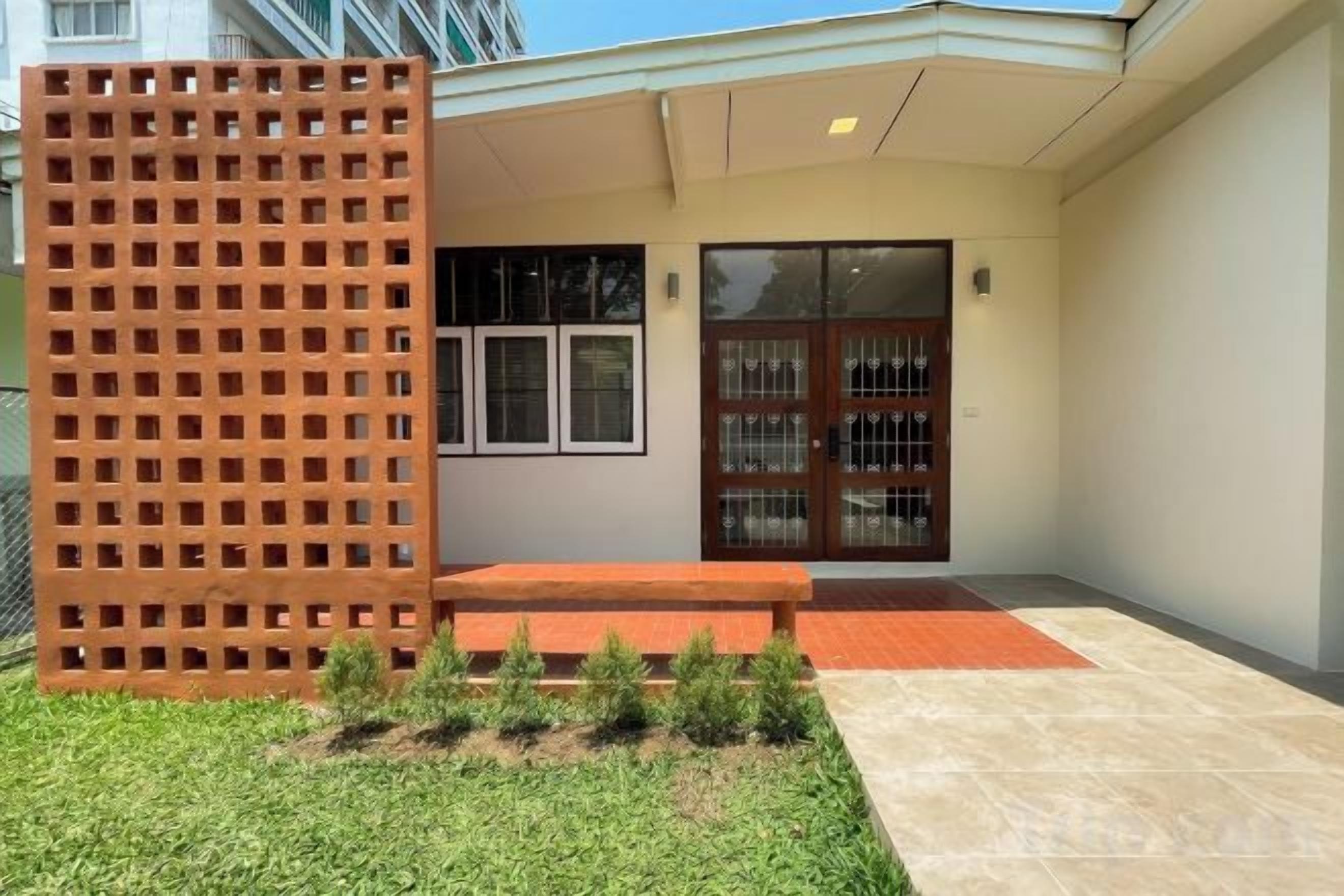 Une entrée d’immeuble avec une clôture en bois, un banc et un petit espace aménagé en jardin.