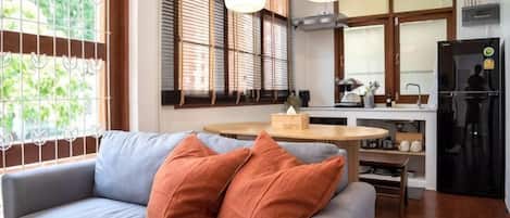 Una sala de estar con sofá, una mesa de comedor y una cocina al fondo.