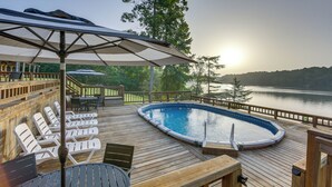 Eine Holzterrasse mit Pool, Liegestühlen und einer überdachten Sitzgelegenheit.